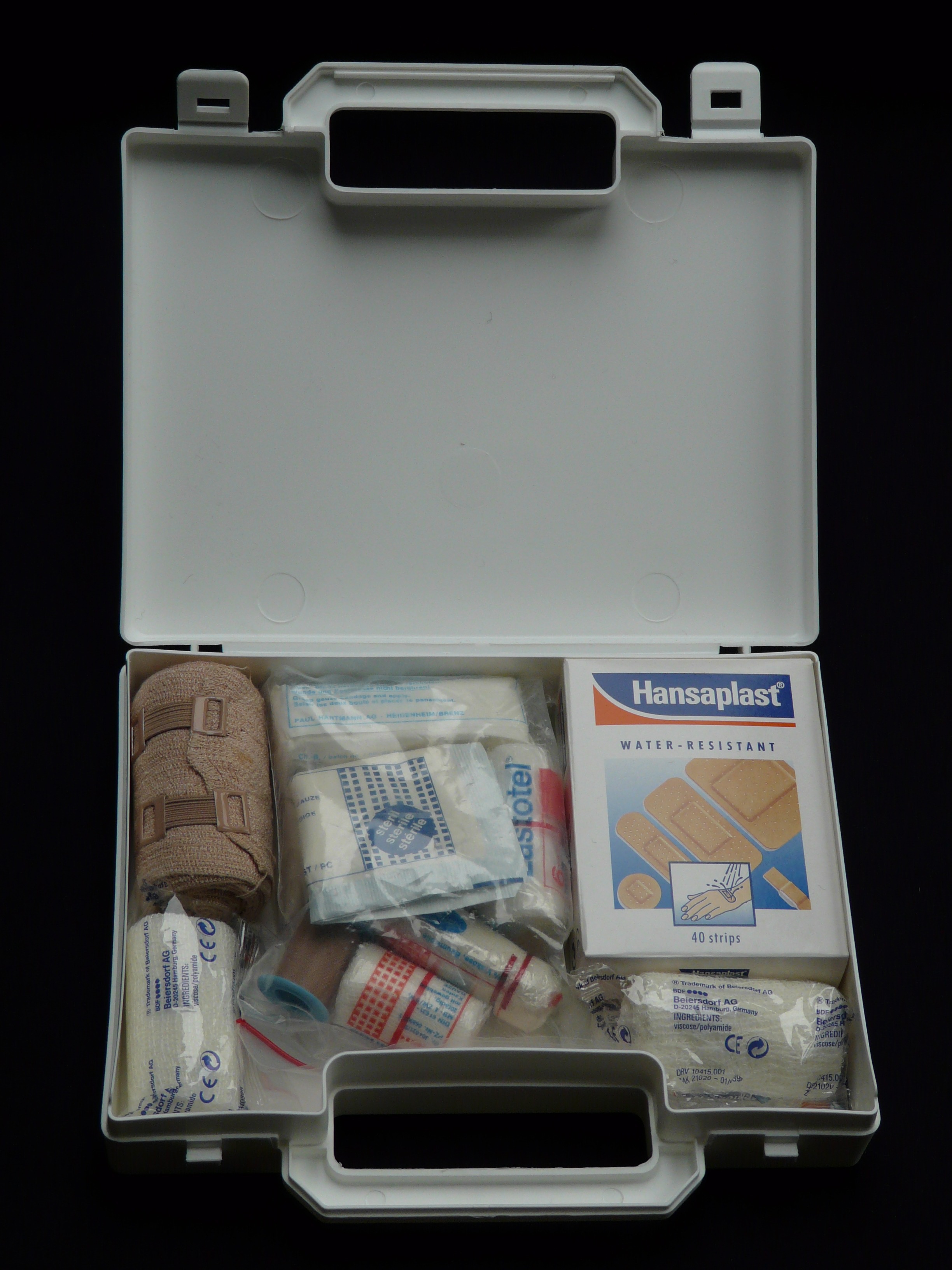 First Aid Kit White first aid kit full of bandaids on a black background